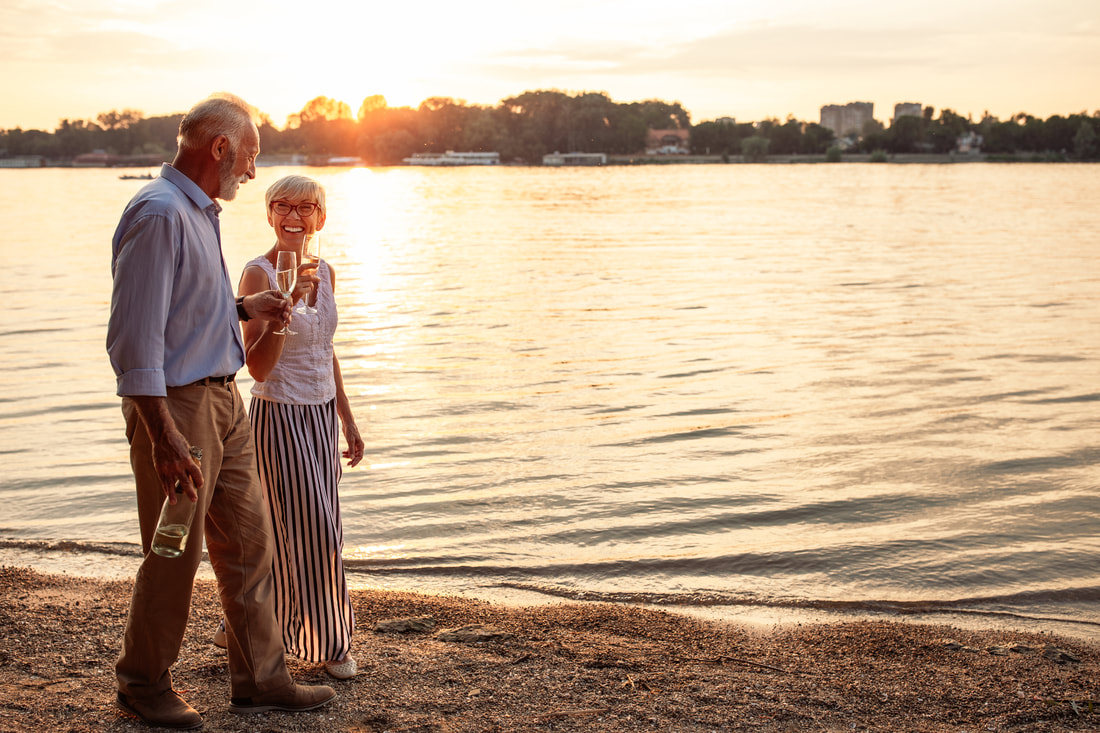 A man and a woman walking along a beach while drinking alcohol